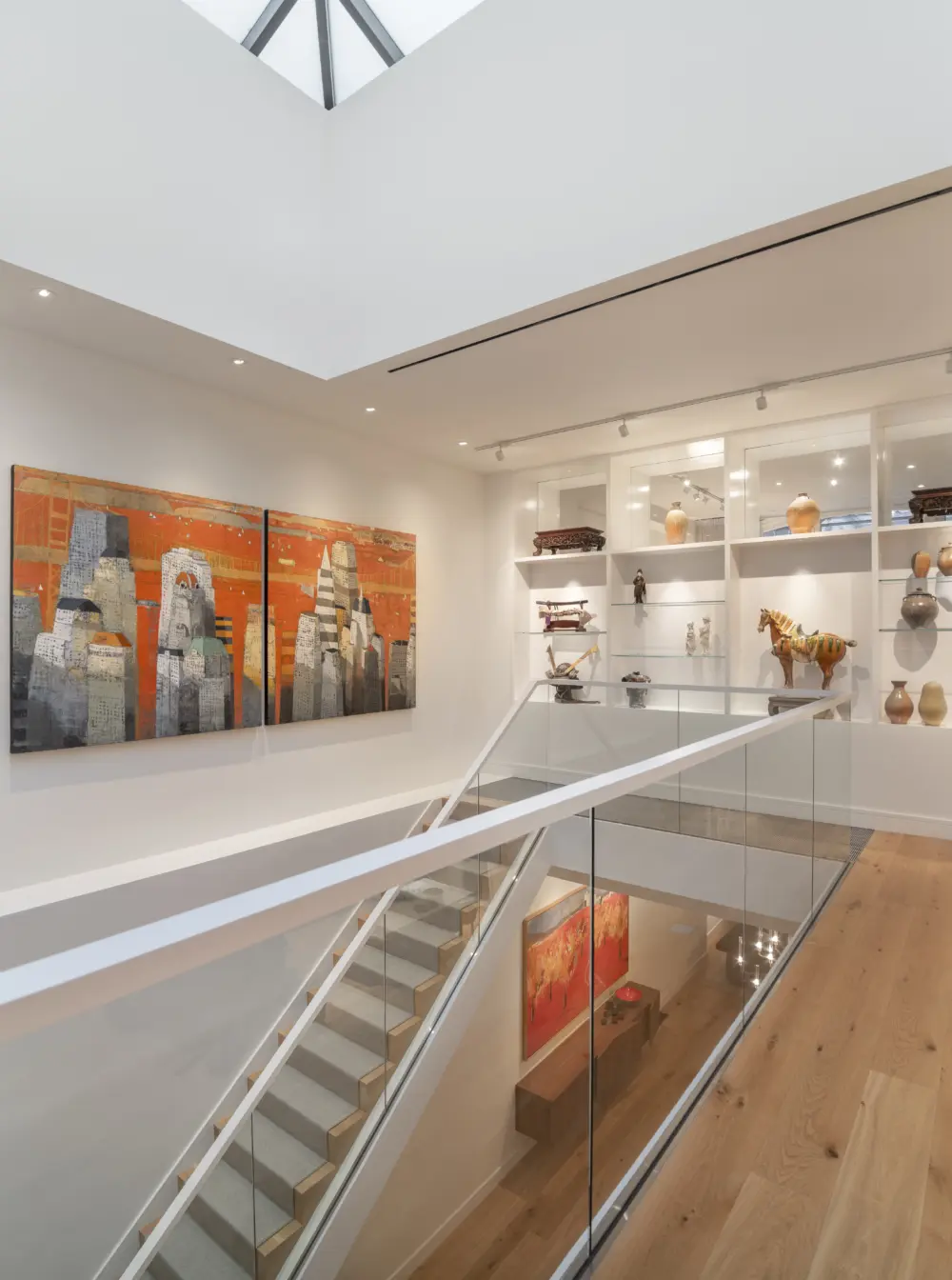 Staircase leading up to open gallery shelving space and skylight