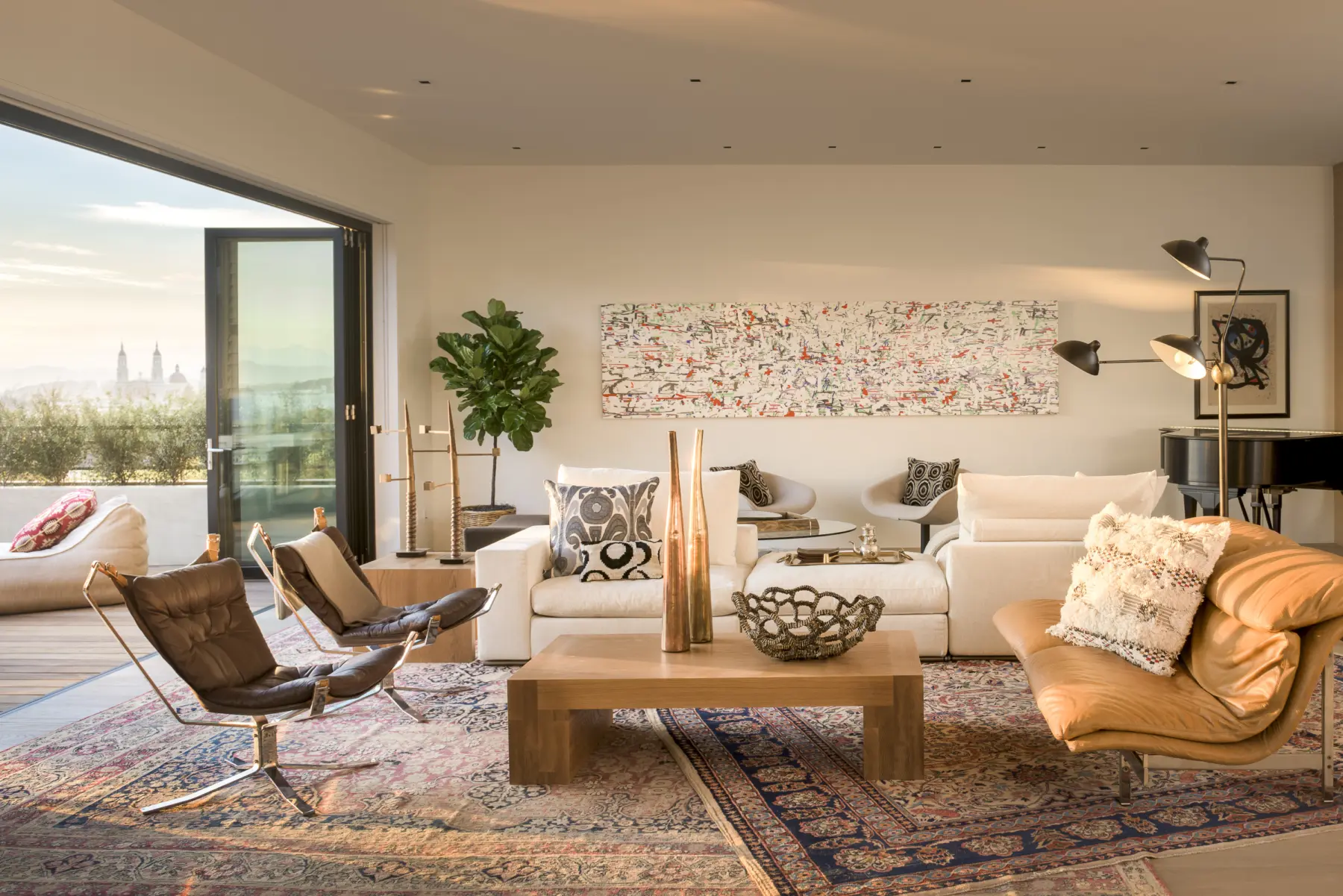 Living room with layered rugs, modern furniture, and bold art pieces with a deck overlooking the city of San Francisco