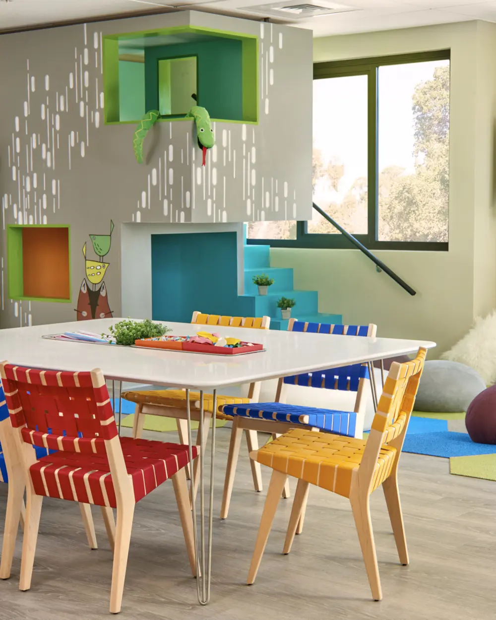 Colorful kids playroom featuring table, chairs and play space