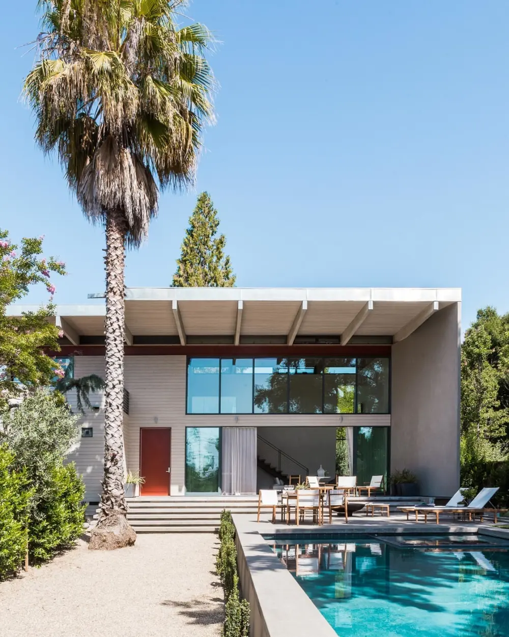 Modern home with large roof overhang, swimming pool and palm tree
